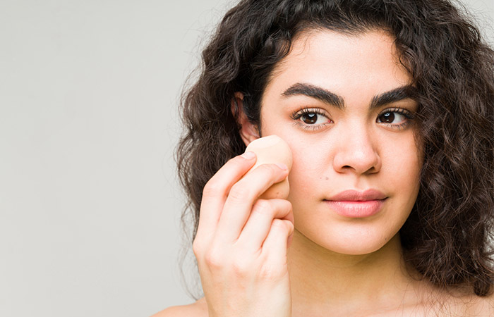 Woman using sponge to blend makeup for a natural look