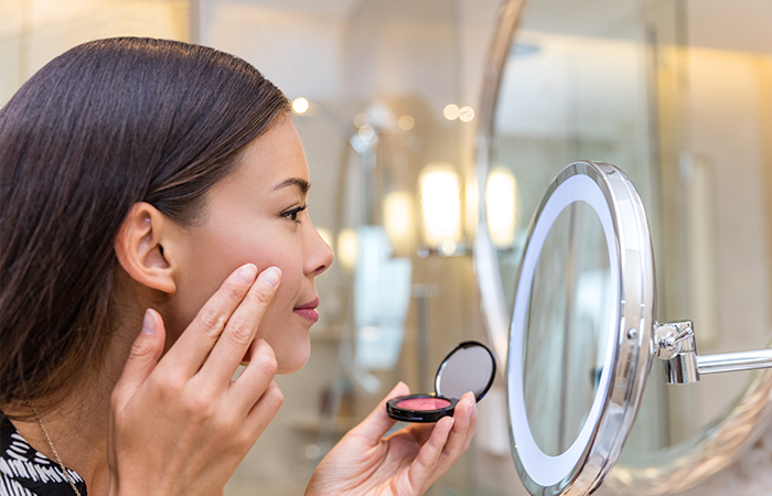 Woman applying cream blush with fingertips